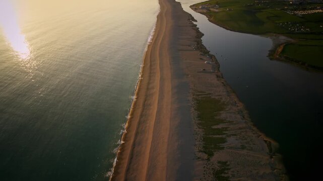 Aerial footage revealing a long, narrow sandbar separating the ocean from a lagoon at sunrise
