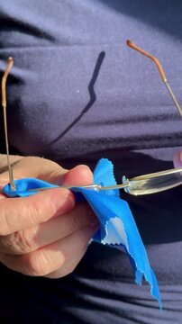 Closeup hands cleaning eyeglasses with satin cloth, woman gently polishes gold frames and lenses, sunlight highlights microfiber