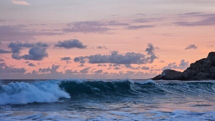 Powerful ocean waves crashing and rolling against rocky coast cliffs under a dramatic pink sunset © Alvaro