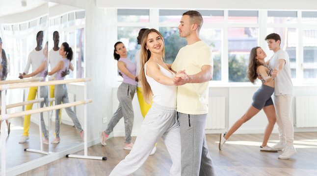 Graceful young girl and boy training waltz dance poses in dancehall during workout session