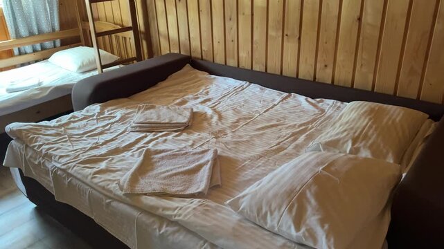 Warm forest cabin with wooden walls, white bedding, double bed and bunk bed designed for comfortable outdoor travel and cozy family accommodation.