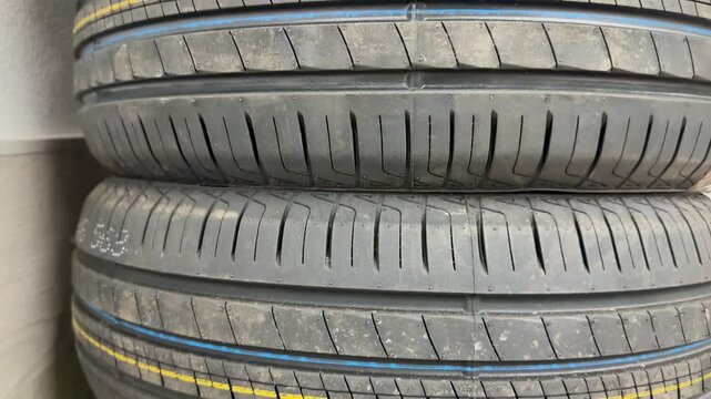 Stacked summer tires macro shot showing detailed tread patterns with colorful factory lines rubber texture multiple new passenger