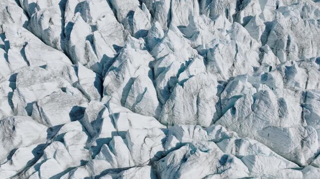 Aerial drone view of glacier cracks and ice surface texture. Abstract frozen nature background with crevasses and arctic pattern from above.