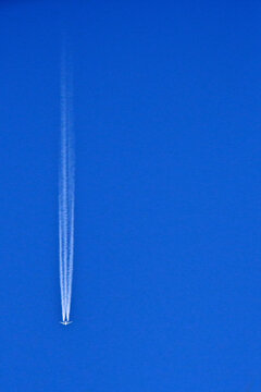 A two-engine jet producing three contrails because the drop in air pressure behind the fuselage and wings creates a third, invisible band of water vapor that condenses into a icy contrail 