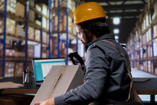 Storehouse worker managing quality control on merchandise, scanning barcodes on depot boxes to create dispatch notes for inventory. Supply manager verifying import/export details.