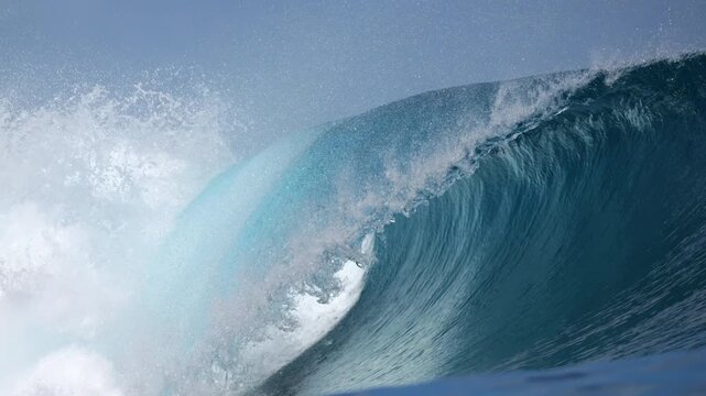 CLOSE UP, SLOW MOTION: Flawless barrel wave wraps into a glowing blue cylinder as white spray lifts off the lip. Classic Mentawai reef break in motion, full of tropical color and pure ocean power.