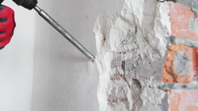 Close up of power tool drilling wall during demolition in apartment. Concept of home renovation and construction repair.
