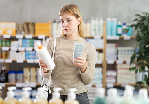 Girl in autumn clothes choosing skin cream at the drugstore