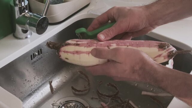 Male hands peeling cassava root also called manioc or yuca, Manihot preparing tropical tuber for cooking, fresh Manihot esculenta from farm harvest, traditional food ingredient in many world cuisines
