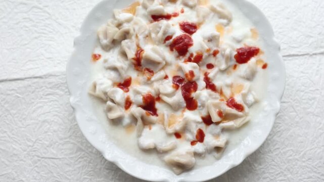 Close-up of traditional Turkish manti dumplings served with garlic yogurt and spicy butter sauce