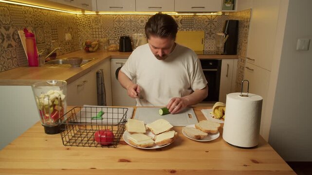 Man slicing cucumber on cutting board in rustic kitchen morning