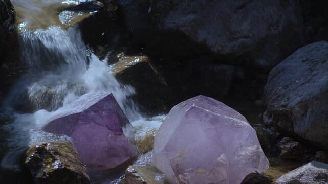 Hidden Grotto With Gentle Waterfall Cascading Over Smooth Violet Tinted Crystals In An Underground Cave