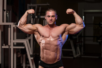 Fototapeta premium Muscular Man Is Hitting Rear Double Bicep Pose