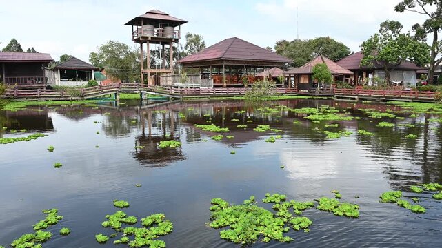 Floating wooden house on calm lake surrounded by lush green mountains and mist in Khao Sok National Park, Surat Thani, Thailand; serene eco-resort travel destination during morn