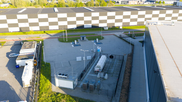 Roosendaal, Netherlands - 25 April 2026: Aerial view of an industrial facility with a checkered facade building and a white tanker truck parked in a fenced lot.