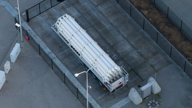 Roosendaal, Netherlands - 25 April 2026: Aerial view of a trailer loaded with white pressurized gas cylinders parked within a fenced industrial compound.