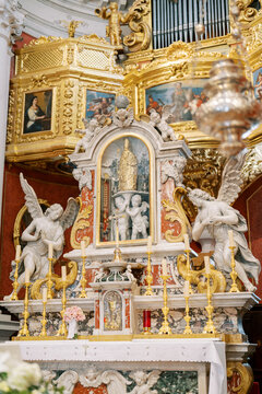 Exquisite gilded Baroque shrine. Ornate golden altar featuring cherubs and artistic panels nearby