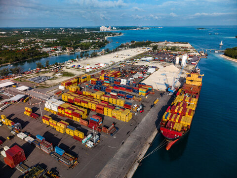 Nassau, The Bahamas - 02 June 2026: Aerial view of Arawak Cay port featuring rows of colorful shipping containers and a large cargo vessel docked at the pier under a clear sky.