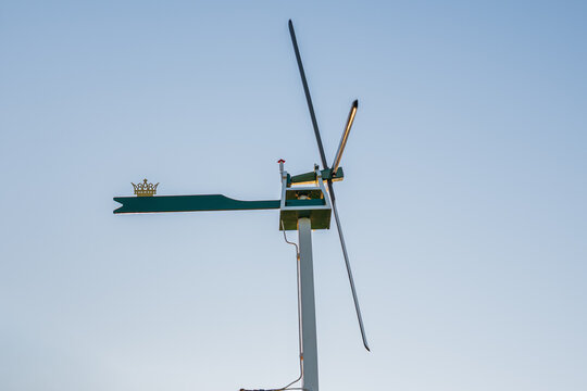 Vintage weather vane with crown symbol and wind propeller against clear blue sky, traditional dutch anemometer and meteorology indicator tool in zaanse schans netherlands