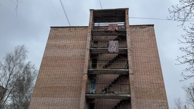 Brick building exterior hanging carpets balconies, weathered hostel end with open staircases and concrete landings, patterned rugs