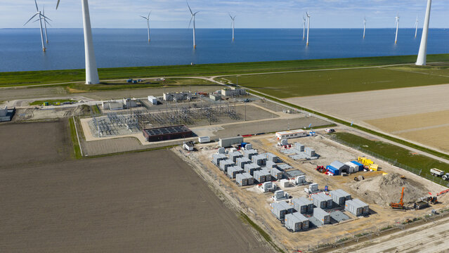 Espel, Netherlands - 04 April 2026: Aerial view of the Westermeerdijk wind farm and power substation with offshore turbines in the IJsselmeer and battery storage units on land.