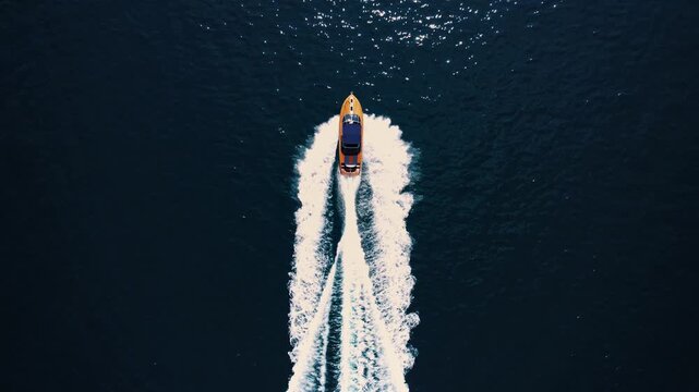 Boat moves through luminous blue ocean creating balanced wake pattern