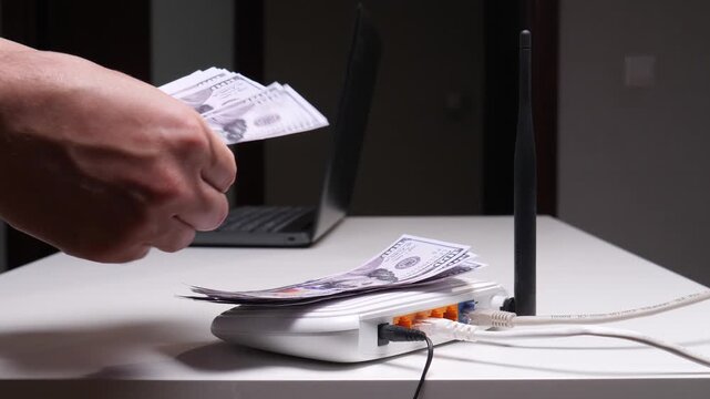 Person's hands putting american dollar banknotes on a wireless internet router, symbolizing earning money through online business, digital transactions, or the digital economy at home