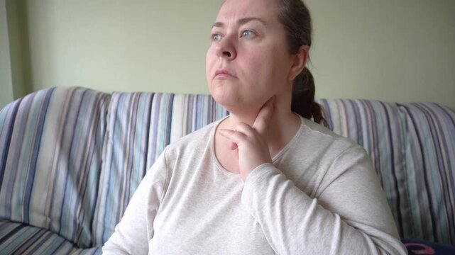 A woman measures the pulse in her neck. A woman checks the pulse in her neck with her hand, monitoring her state of health, the concept of self-diagnosis and attention to the body.