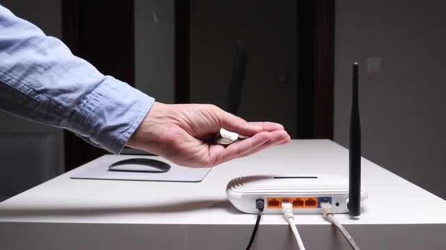 Hand holding coins beside a wi fi router on a desk symbolizes the financial aspect of online connectivity, internet service cost, and modern digital home communication