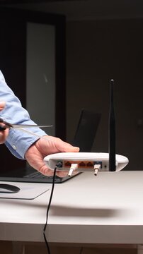Vertical video person's hand holding open scissors near a wireless router and cutting a cable, symbolizing internet disconnection, censorship, or a digital blackout