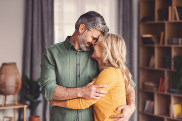 Happy Senior Caucasian Male And Female Embracing Each Other And Smiling At Home, Enjoying Affection...