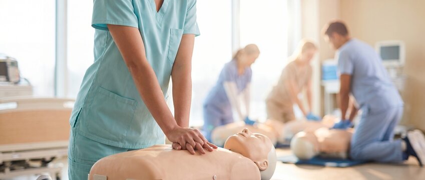 Group cardiopulmonary resuscitation workshop showing man pressing on chest of medical dummy