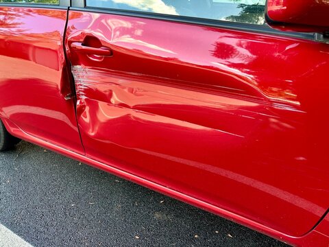 red sports car with dented door