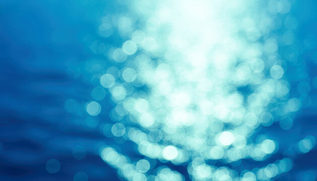Blue water bokeh background. Abstract sparkling sea ocean surface ripple copy space.