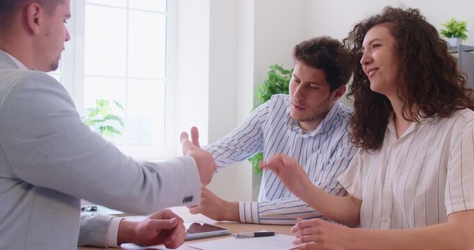 Realtor agent observes signing a property agreement. Broker presents the contract document and confirms mortgage details during a clear meeting. Property purchase and real estate