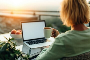 Fototapeta premium Woman working on laptop on balcony at sunset with coffee remote lifestyle evening