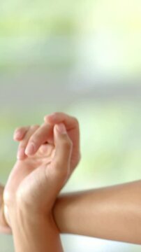 Vertical video: Right hand resting on arm flexing fingers and rotating wrist by window, copy space