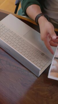 Vertical video: Hands typing green top pausing picking pic moving keyboard showing recipes at table