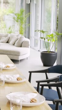 Vertical video: Pulling back from close-up, cam showing table set in dining area with rolls, candle