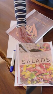 Vertical video: Hands hovering starting striped-top jeans pair sorting covers at home, adding notes