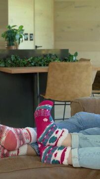 Vertical video: Panning shot showing feet moving in fuzzy socks, jeans on couch, revealing yard