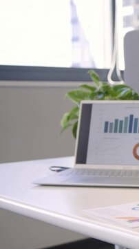 Vertical video: Pulling back, camera revealing laptop and desk at window to show charts and gift