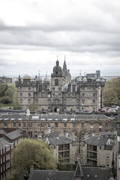 View of the historic George Heriot's School with its ornate towers and clock face overlooking city rooftops under a cloudy sky in Edinburgh, Scotland, United Kingdom.