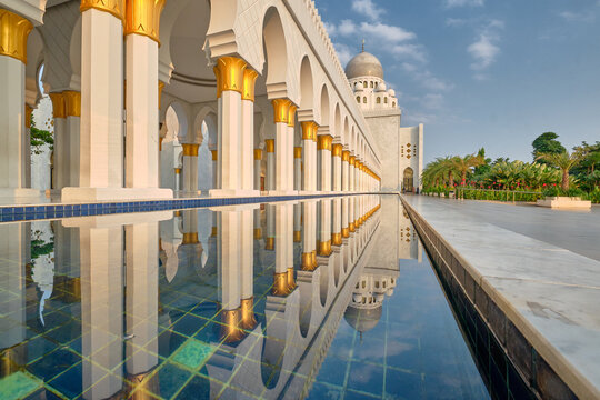 View of the white colonnade and golden-topped pillars of the Sheikh Zayed Grand Mosque Solo Surakarta reflected in a calm pool in Banjarsari, Central Java, Indonesia.