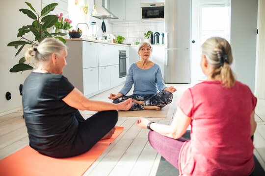 Senior women practicing yoga meditation in a home kitchen