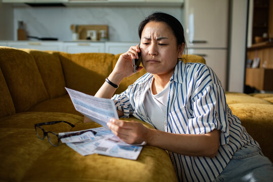 Concerned woman on phone reviewing household bills at home