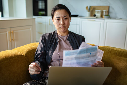 Concerned woman reviewing household bills on sofa at home