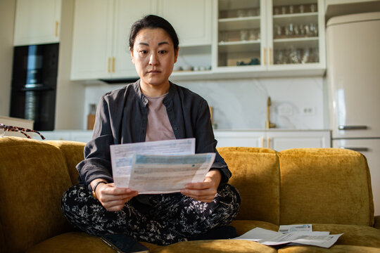 Worried woman reviewing bills on sofa at home