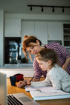 Mother helping daughter with homework at kitchen table