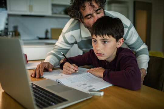 Father tutoring son with homework at home